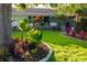 Landscaped front yard featuring vibrant flowerbeds, a mature shade tree, and a well-maintained lawn at 12021 144Th St, Largo, FL 33774