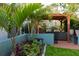 Landscaped patio with pergola offers a relaxing outdoor living space, complemented by tropical plants and garden elements at 12021 144Th St, Largo, FL 33774