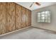 Bedroom with wood paneled accent wall, ceiling fan, carpet, and a window at 14615 Daybreak Dr, Lutz, FL 33559