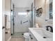 Modern bathroom boasts a glass shower with black hardware, a vanity with white countertops and a decorative shelving unit at 1747 Wood Brook St, Tarpon Springs, FL 34689