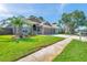 Residential house with green grass and a lush palm tree in the front yard at 1747 Wood Brook St, Tarpon Springs, FL 34689