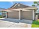 A two car attached garage features paneled doors, concrete driveway, and manicured lawn at 1747 Wood Brook St, Tarpon Springs, FL 34689