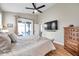 Bright main bedroom featuring a ceiling fan, balcony access, television, and a wooden dresser for ample storage at 1747 Wood Brook St, Tarpon Springs, FL 34689