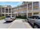 View of condo building with multiple floors and a parking lot with two parked cars at 2021 Shangrila Dr # 14, Clearwater, FL 33763