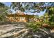 Backyard view showcasing the brick home, mature trees and partial view of a pergola at 2710 N Dundee St, Tampa, FL 33629