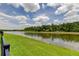 View of a grassy backyard leading to a calm lake surrounded by trees at 2826 Riders Pass, Odessa, FL 33556