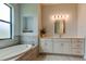 Soaking tub and white vanity in this luxurious bathroom featuring tile accents and a decorative niche with towels at 2826 Riders Pass, Odessa, FL 33556