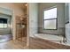 Elegant bathroom with a frameless glass shower, large garden tub, and bright natural light from the window at 2826 Riders Pass, Odessa, FL 33556