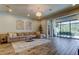 Spacious living room features stylish chandelier, large sectional sofa, and sliding glass doors to outdoor area at 2826 Riders Pass, Odessa, FL 33556