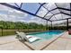 View of pool featuring submerged lounge chairs and patio seating with screened enclosure at 2826 Riders Pass, Odessa, FL 33556