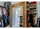 Organized walk-in closet with custom shelving, hanging space, and a mirror offering a glimpse into the luxurious bathroom at 2826 Riders Pass, Odessa, FL 33556