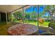 Screened porch with a table and chairs offers views of the green yard with mature trees at 3086 Pointer Dr, Palm Harbor, FL 34683