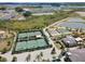 Drone shot of the tennis courts, shuffleboard court, and bocce ball court surrounded by ponds and greenery at 31354 Cabana Rye Ave, San Antonio, FL 33576