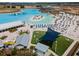 Aerial view of the community lagoon featuring beach, umbrellas, lounge chairs, and blue shade structure at 31354 Cabana Rye Ave, San Antonio, FL 33576