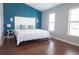 Bedroom with hardwood floors, white bedding, and a vibrant blue accent wall at 320 Crosswinds Dr, Palm Harbor, FL 34683