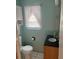 Bathroom with a toilet, window, cabinet with sink, and white tile flooring at 3210 W North B St, Tampa, FL 33609