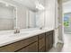 Bathroom featuring double sinks, white countertops, a large mirror, and a view from the window at 3737 Nandina Cir, Sun City Center, FL 33573