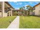 Beautifully landscaped courtyard with mature trees, lush green grass, and sidewalk leading to two-story building at 404 Hammock Pine Blvd # 404, Clearwater, FL 33761
