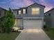 Two-story home featuring light blue siding, a gray roof, attached two car garage, and a well-maintained lawn at dusk at 413 Royal Empress Dr, Ruskin, FL 33570