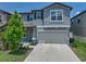 Two-story home featuring light blue siding, a gray roof, attached two car garage, and a well-maintained lawn at 413 Royal Empress Dr, Ruskin, FL 33570