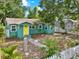 Inviting home featuring a yellow door, well-manicured lawn, and a quaint white picket fence at 4330 7Th N Ave, St Petersburg, FL 33713