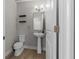 Modern half-bathroom with pedestal sink, wood floors, and floating shelves at 444 49Th N St, St Petersburg, FL 33710