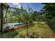The backyard of the home features mature landscaping around the screened-in pool at 4452 Bardsdale Dr, Palm Harbor, FL 34685