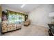 Bright living room with large window featuring palm tree decorations, patterned chair and ottoman, and neutral walls at 4452 Bardsdale Dr, Palm Harbor, FL 34685