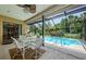 Covered patio with table and chairs overlooking the pristine pool and lush, tropical landscaping at 4452 Bardsdale Dr, Palm Harbor, FL 34685