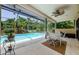 View of the pool and patio area, surrounded by a screened enclosure and lush landscaping at 4452 Bardsdale Dr, Palm Harbor, FL 34685