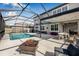Beautiful backyard featuring a screened-in pool, outdoor seating area, and a fire pit for entertaining at 4808 Jackson Club Loop, Tampa, FL 33624