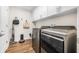Well-lit laundry room featuring modern washer and dryer units, wooden floors, and storage cabinets at 4808 Jackson Club Loop, Tampa, FL 33624