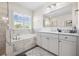 Elegant bathroom featuring a soaking tub and separate shower, accented by marble tiling and white cabinetry at 4808 Jackson Club Loop, Tampa, FL 33624