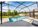 Relaxing screened-in pool with a concrete deck and view of the green lawn and pond at 4808 Jackson Club Loop, Tampa, FL 33624