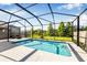Inviting screened-in pool with a concrete deck and a view of the green lawn and pond at 4808 Jackson Club Loop, Tampa, FL 33624