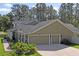 Charming home featuring a three-car garage, tan exterior, and well manicured landscaping at 5458 Zamia Dr, Brooksville, FL 34604