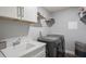 Modern laundry room with washer, dryer, sink, white cabinets, and storage for convenience at 5458 Zamia Dr, Brooksville, FL 34604