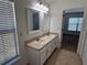 Bathroom featuring a double sink vanity, two mirrors, and natural light from the window at 5527 Kinglethill Dr, Lithia, FL 33547