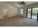 Cozy bedroom with neutral carpet, window, and sliding glass doors to a balcony, creating a relaxing retreat at 5527 Kinglethill Dr, Lithia, FL 33547