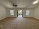 Open living room with neutral carpeting, ceiling fan, and sliding glass doors to a balcony at 5527 Kinglethill Dr, Lithia, FL 33547