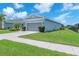 Side view of single-story home with a two-car garage, manicured lawn, and blue siding against a sunny sky at 5539 Silver Sun Dr, Apollo Beach, FL 33572