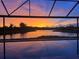 Orange sunset over a lake seen from behind a pool enclosure at 5539 Silver Sun Dr, Apollo Beach, FL 33572