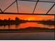 Fiery orange sunset reflecting on the lake viewed from the screened-in pool enclosure at 5539 Silver Sun Dr, Apollo Beach, FL 33572