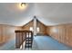 Attic with blue carpet and wood paneled walls featuring vaulted ceilings and natural lighting at 5603 Palmetto Rd, New Port Richey, FL 34652