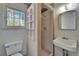 Small bathroom features a stand up shower, a toilet, and a sink, illuminated by a window at 5603 Palmetto Rd, New Port Richey, FL 34652