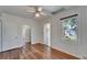 Bedroom with hardwood floors, crisp white wall paneling, large window, and a ceiling fan at 5603 Palmetto Rd, New Port Richey, FL 34652