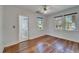 Bedroom with hardwood floors, crisp white wall paneling, two large windows, and a ceiling fan at 5603 Palmetto Rd, New Port Richey, FL 34652