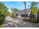 View of the home's two-car garage, with lush landscaping and brick-paved driveway at 5610 N River Shore Dr, Tampa, FL 33603