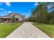 Long paver driveway leading to a two-story home with lush landscaping and mature trees at 5865 Creek Ridge Rd, Brooksville, FL 34601