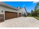 Three-car garage with brown doors, stone accents, and a large paved driveway at 5865 Creek Ridge Rd, Brooksville, FL 34601